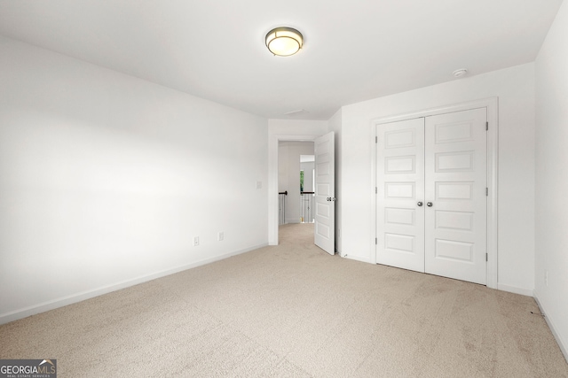 unfurnished bedroom featuring light colored carpet and a closet