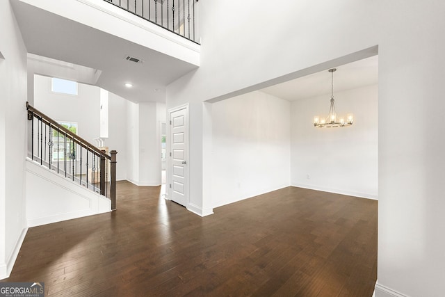 interior space featuring a towering ceiling, a chandelier, and dark hardwood / wood-style floors