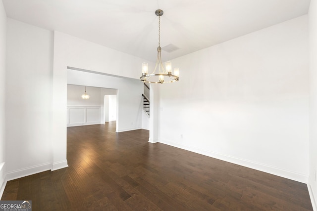 unfurnished room featuring a notable chandelier and dark wood-type flooring