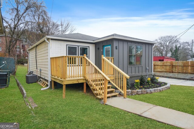 view of front of house with central AC unit, a deck, and a front lawn