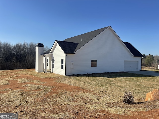 view of side of property with a chimney, a lawn, and an attached garage