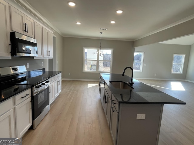 kitchen with visible vents, a kitchen island with sink, stainless steel appliances, pendant lighting, and a sink