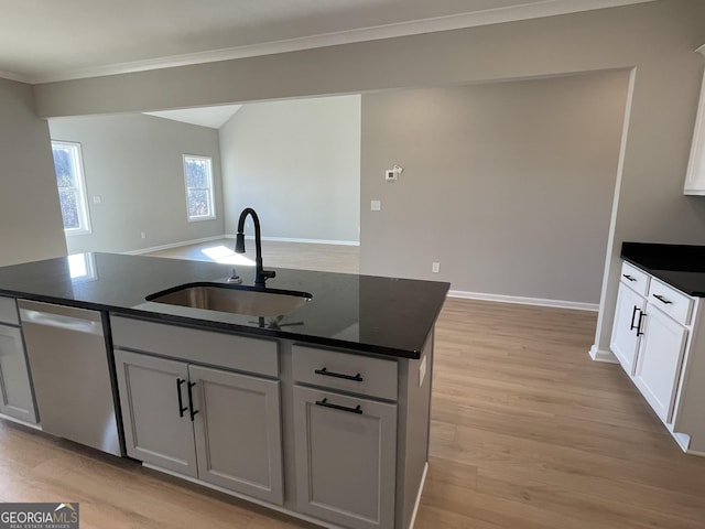 kitchen featuring light wood finished floors, white cabinetry, a sink, an island with sink, and dishwasher