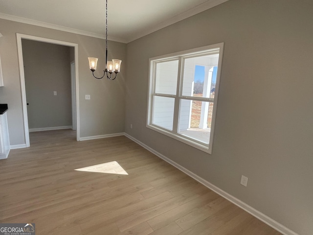 unfurnished dining area featuring baseboards, light wood-style flooring, a chandelier, and crown molding