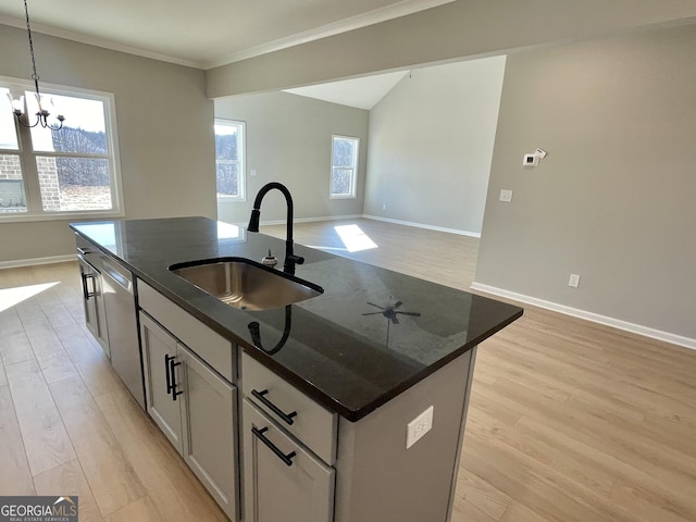 kitchen featuring a center island with sink, hanging light fixtures, open floor plan, a sink, and dark stone counters