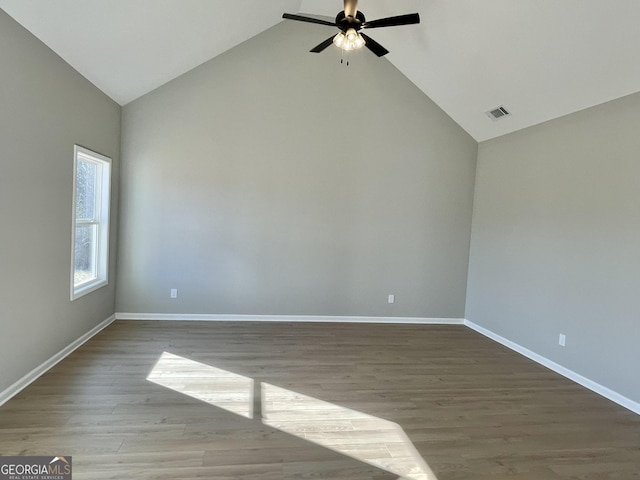 empty room with light wood-style floors, baseboards, visible vents, and high vaulted ceiling