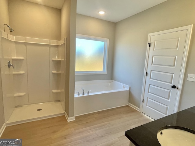 full bath with a shower, a garden tub, vanity, wood finished floors, and baseboards