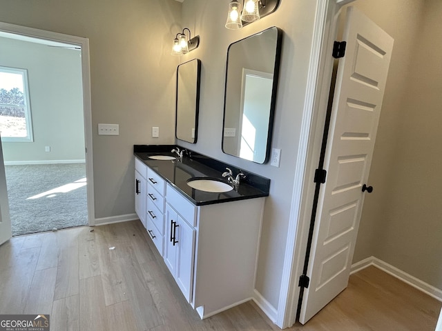 bathroom featuring double vanity, a sink, baseboards, and wood finished floors