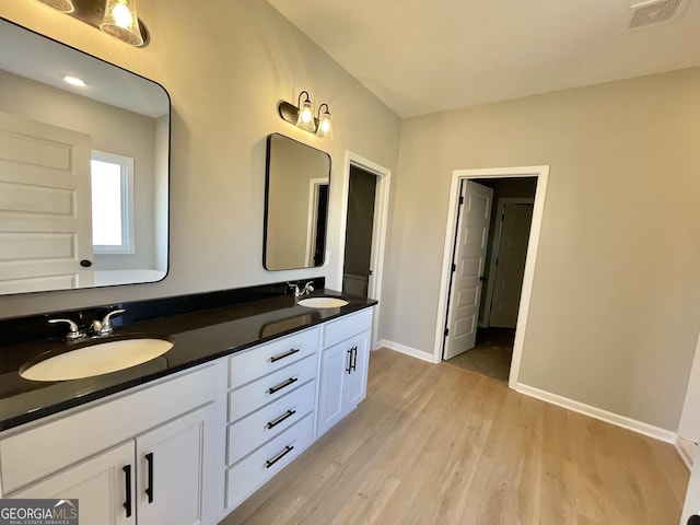 full bath featuring double vanity, wood finished floors, a sink, and visible vents