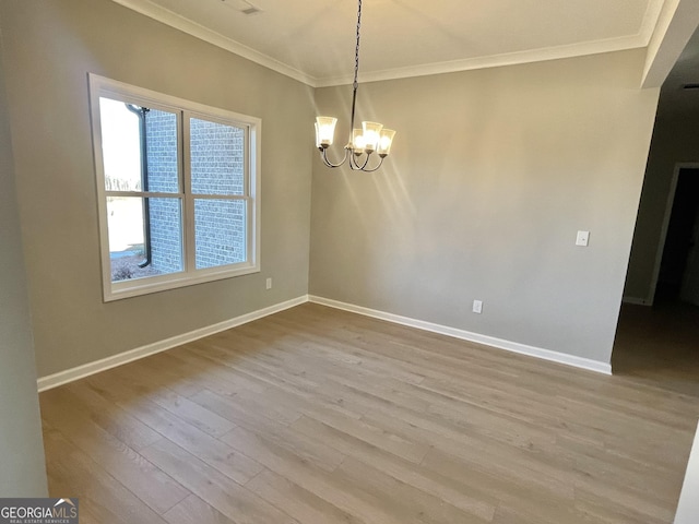 spare room with light wood finished floors, ornamental molding, baseboards, and an inviting chandelier