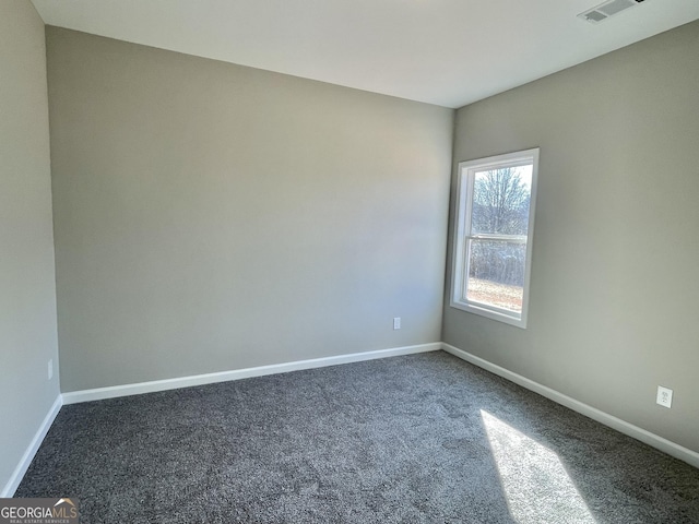 empty room with dark colored carpet, visible vents, and baseboards