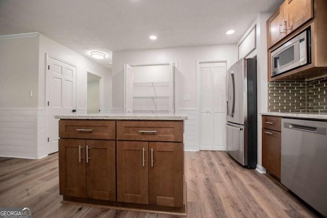 kitchen featuring light stone countertops, a center island, light wood-type flooring, and appliances with stainless steel finishes