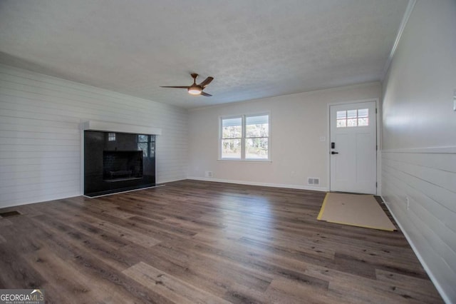 unfurnished living room with a textured ceiling, ceiling fan, dark hardwood / wood-style flooring, and crown molding