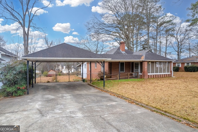 single story home with a carport, a sunroom, and a front lawn