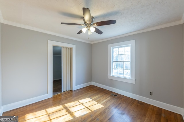 spare room with crown molding, hardwood / wood-style flooring, visible vents, and baseboards