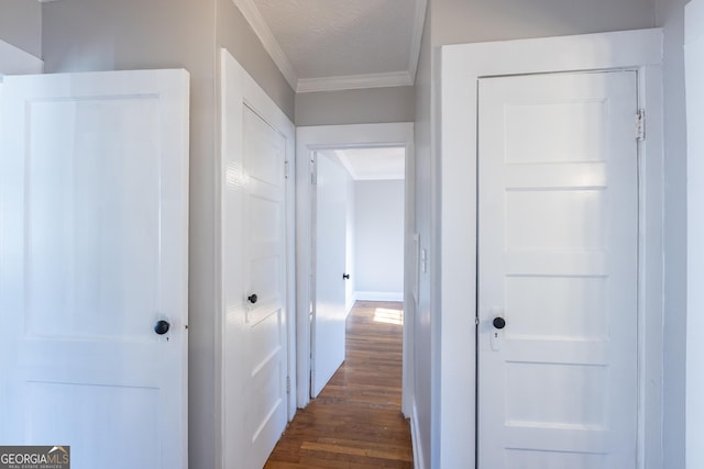 hallway with ornamental molding, dark wood-style flooring, and a textured ceiling