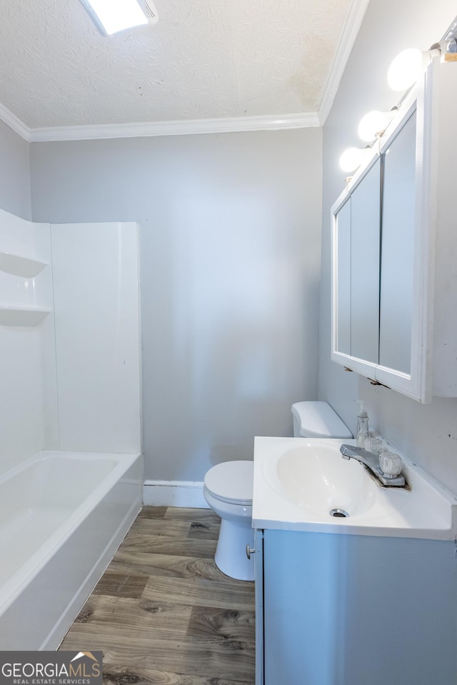 bathroom featuring toilet, vanity, wood finished floors, crown molding, and a textured ceiling