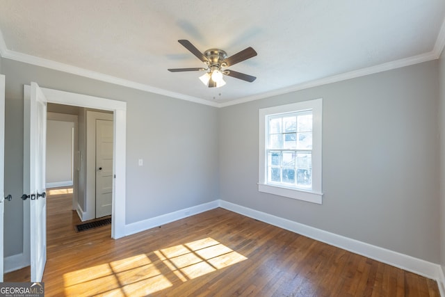 spare room with a ceiling fan, wood-type flooring, baseboards, and crown molding