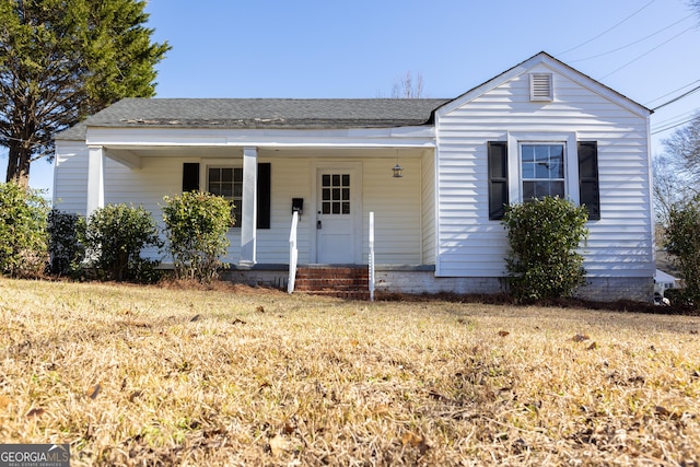 view of front of house with covered porch, roof with shingles, and a front lawn