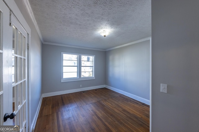 spare room with dark wood-style floors, ornamental molding, a textured ceiling, and baseboards