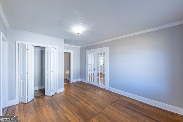 unfurnished bedroom featuring baseboards, ornamental molding, french doors, a closet, and dark wood finished floors