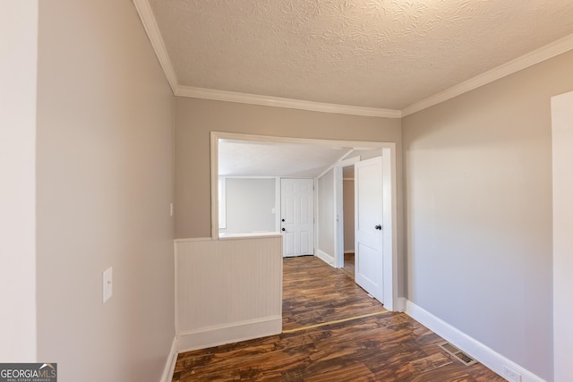 hallway with baseboards, visible vents, dark wood-style flooring, crown molding, and a textured ceiling