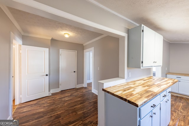 kitchen featuring white cabinets, dark wood-style floors, butcher block counters, crown molding, and a textured ceiling