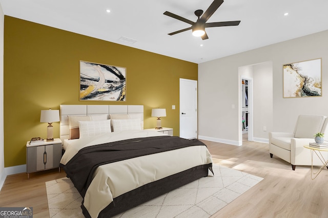 bedroom featuring ceiling fan, a closet, a spacious closet, and light hardwood / wood-style flooring