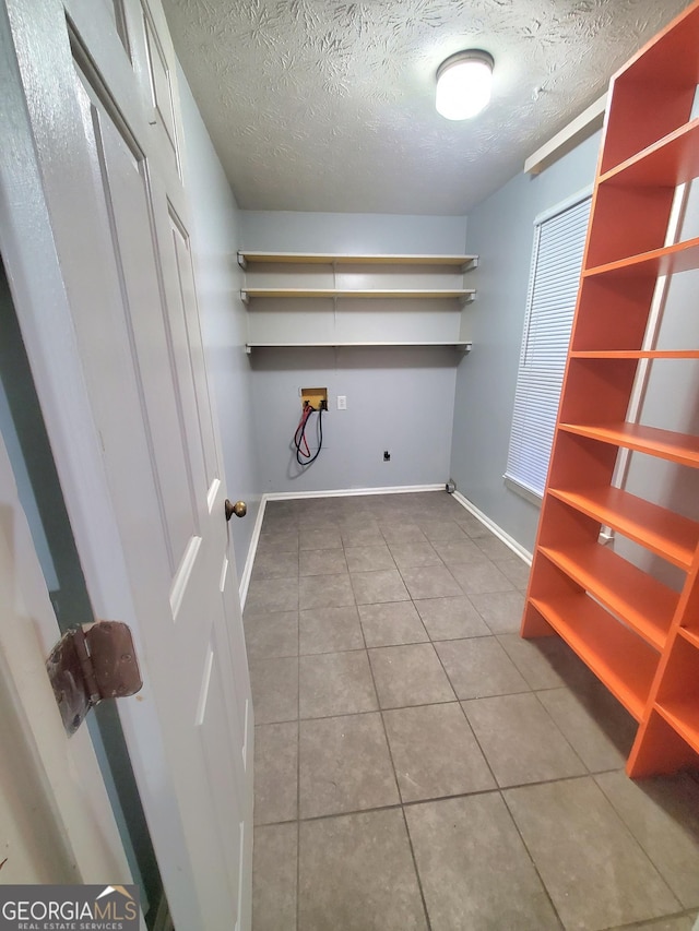 clothes washing area with hookup for a washing machine, a textured ceiling, and tile patterned floors