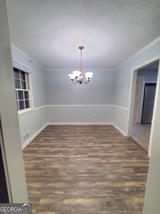 unfurnished room with dark hardwood / wood-style flooring, a chandelier, a textured ceiling, and ornamental molding