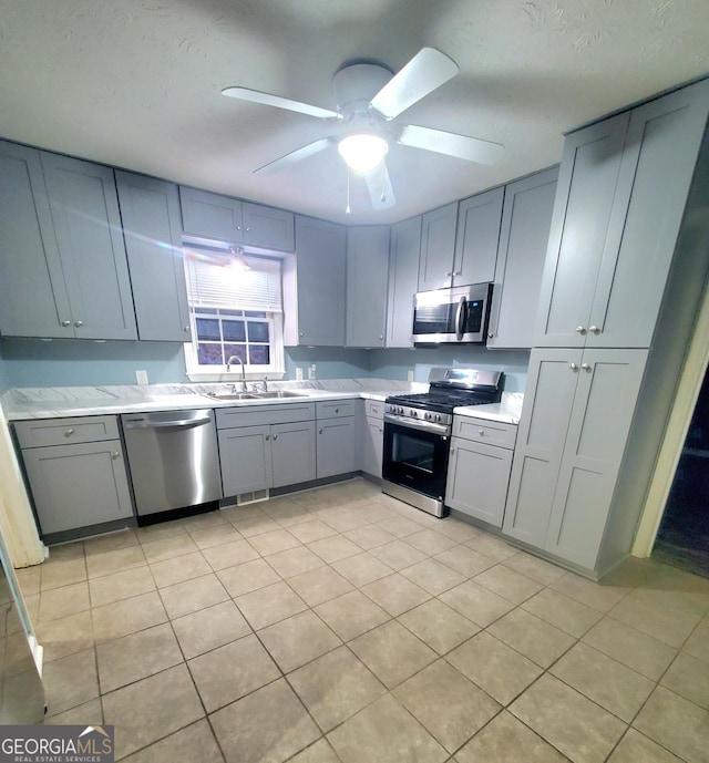 kitchen featuring appliances with stainless steel finishes, gray cabinets, light tile patterned floors, and sink