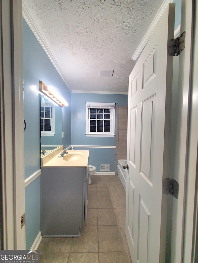 full bathroom featuring tile patterned flooring, a textured ceiling, toilet, vanity, and ornamental molding