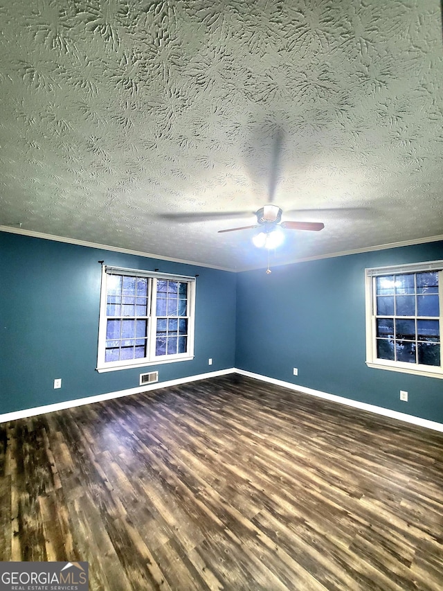 unfurnished room with baseboards, visible vents, crown molding, and wood finished floors