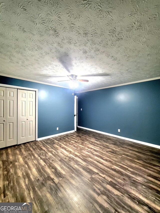 unfurnished bedroom featuring ceiling fan, ornamental molding, a textured ceiling, and dark wood-type flooring