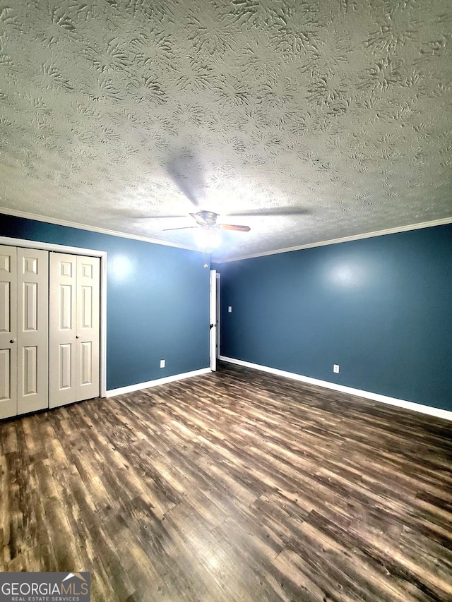 unfurnished bedroom featuring crown molding, a textured ceiling, baseboards, and wood finished floors