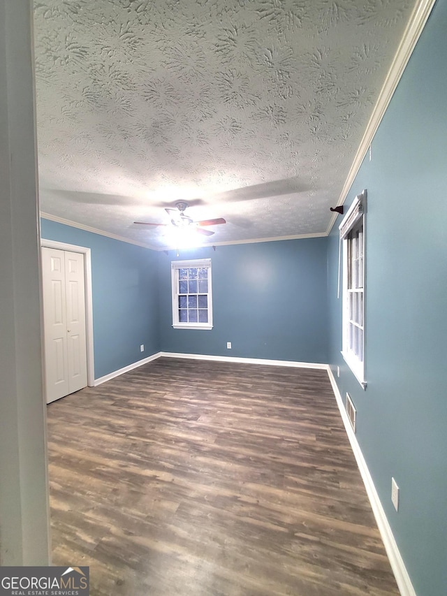 spare room featuring crown molding, visible vents, a ceiling fan, wood finished floors, and baseboards