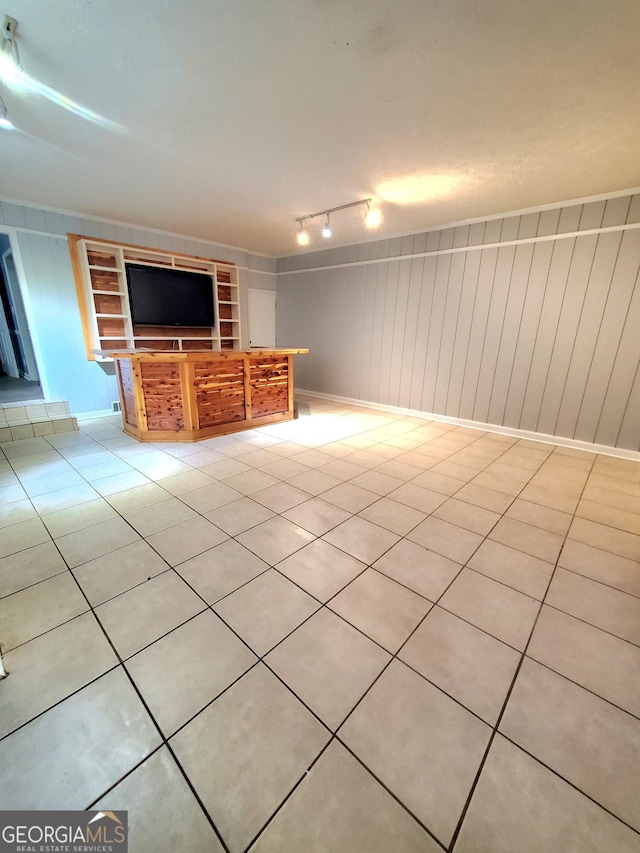 unfurnished living room with built in shelves, rail lighting, light tile patterned flooring, and baseboards