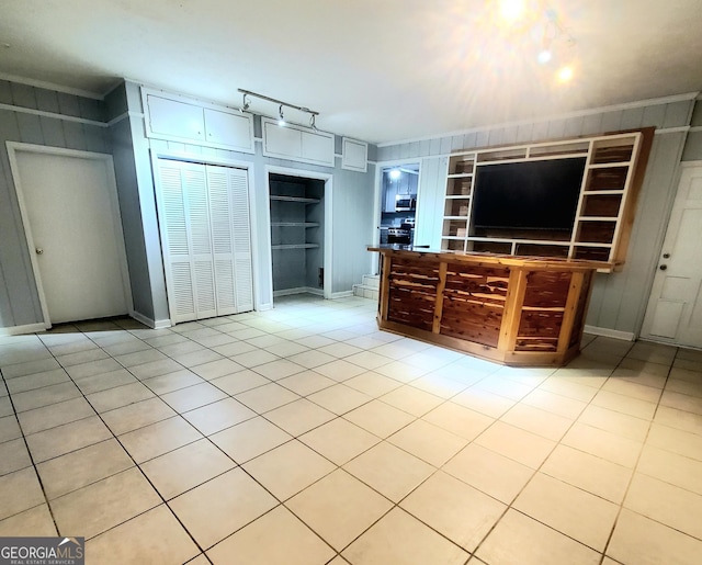 unfurnished living room featuring rail lighting, baseboards, light tile patterned floors, and built in features