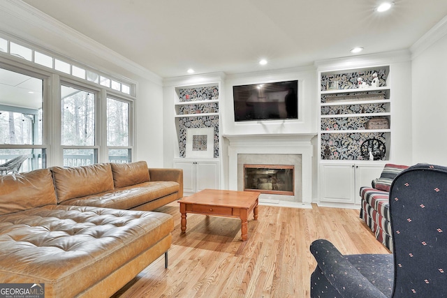 living room with a fireplace, built in shelves, light hardwood / wood-style flooring, and crown molding