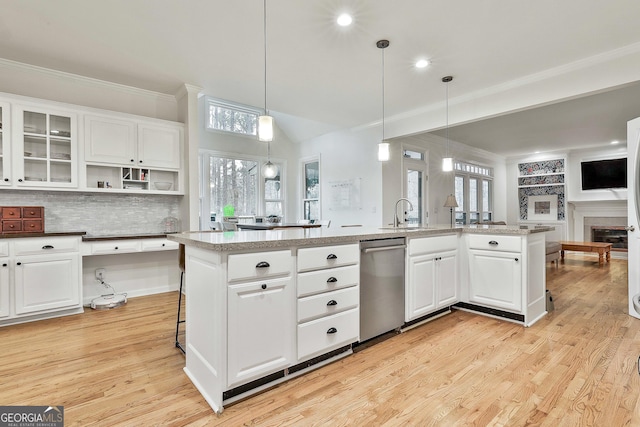 kitchen featuring decorative backsplash, decorative light fixtures, white cabinetry, and a kitchen island with sink