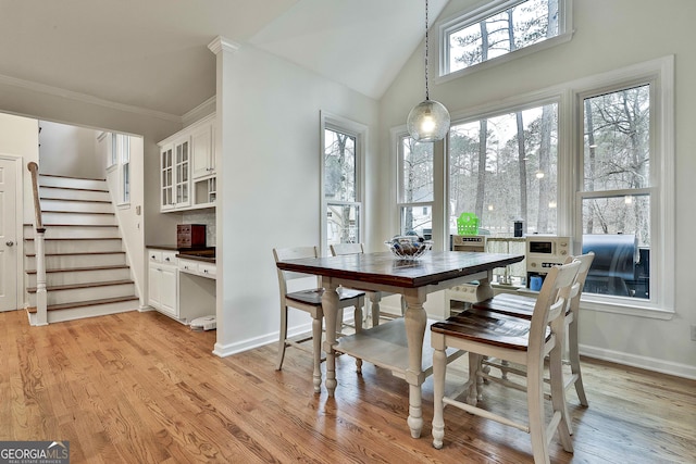 dining area featuring light hardwood / wood-style flooring, vaulted ceiling, and ornamental molding