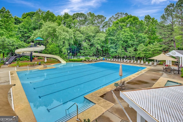 view of swimming pool with a patio and a water slide