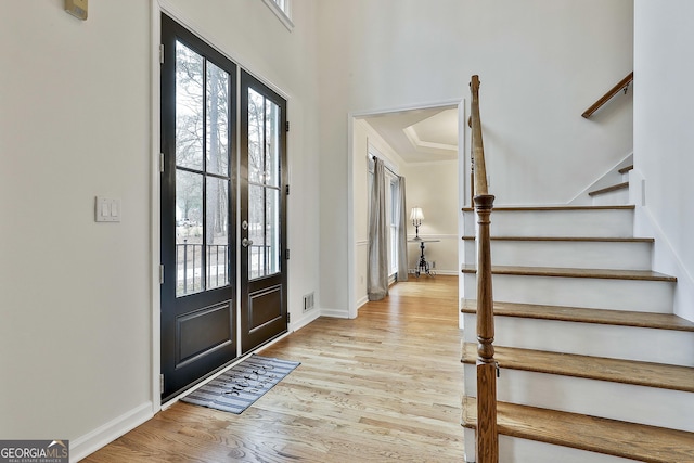 foyer entrance with french doors, light hardwood / wood-style flooring, and crown molding