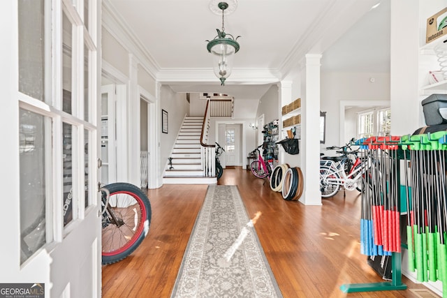 foyer featuring decorative columns, hardwood / wood-style flooring, and ornamental molding