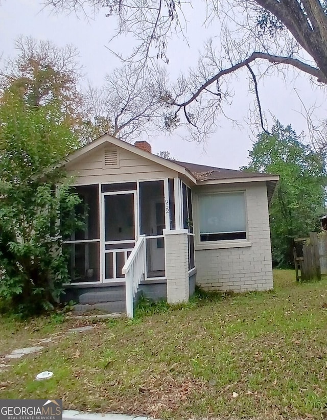 rear view of property featuring a lawn and a sunroom