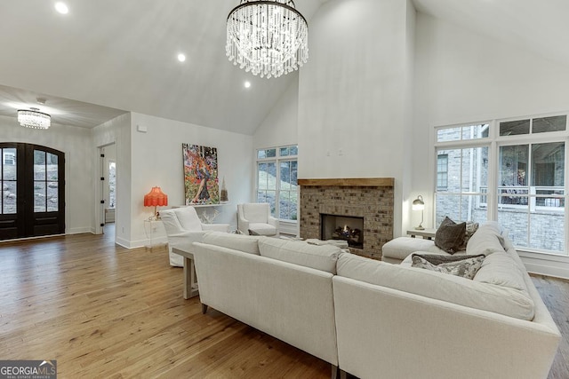 living room featuring french doors, a wealth of natural light, light wood-type flooring, and a notable chandelier