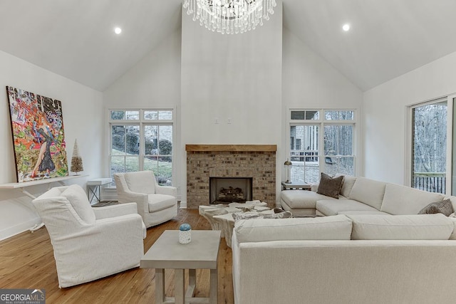 living room with a brick fireplace, light hardwood / wood-style flooring, high vaulted ceiling, and plenty of natural light