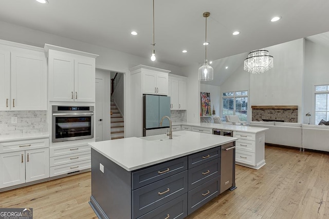 kitchen featuring a center island with sink, fridge, stainless steel oven, and white cabinets