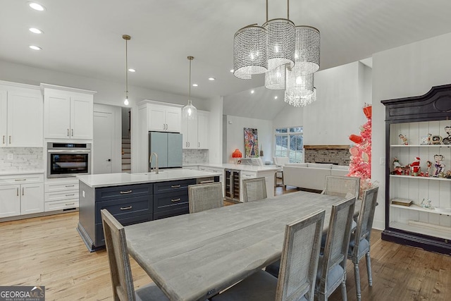 kitchen with pendant lighting, white cabinetry, appliances with stainless steel finishes, and an island with sink