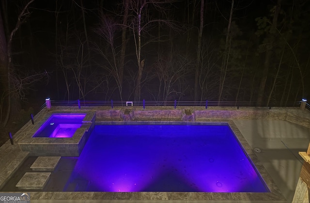 pool at night with an in ground hot tub